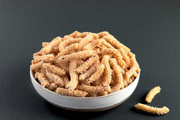 Indian Murukku snack in bowl on dark background. Traditional crispy rice flour snack for festive.