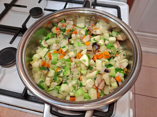 Vegetable stew is cooked on gas stove. Ragout is cooked in metal pan