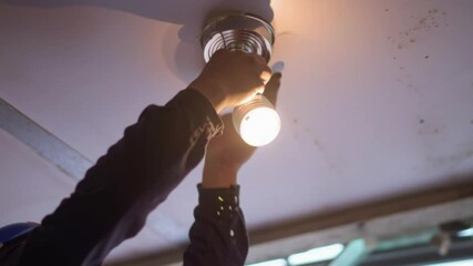 Close up view Electrician repairing ceiling light fixture with screwdriver tool, professional electrical maintenance concept showing skilled technician working on wiring connection for indoor lighting