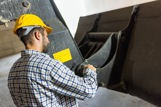 Warehouse mechanic repairing skid steer loader used for soy transport