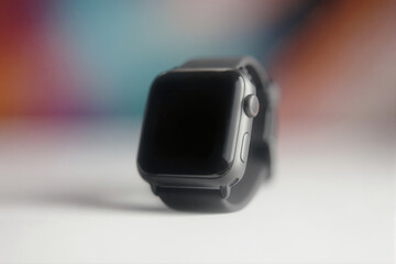 Black smartwatch on a white surface with colorful background