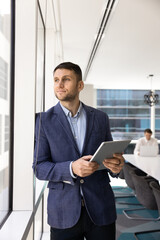 Fototapeta premium Positive dreamy male executive holding digital touchpad