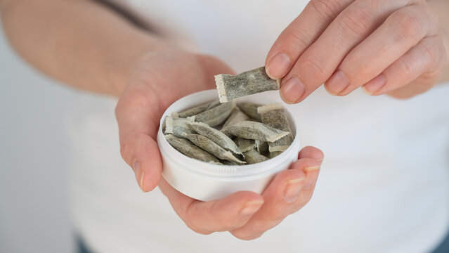 A woman holds a jar of chewing tobacco. 