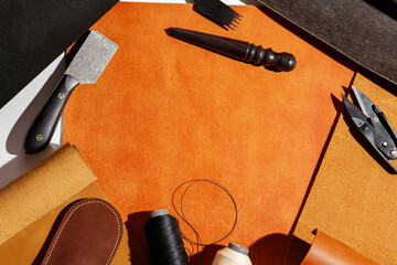 Leather crafting tools and materials on orange background. Mockup. Copyspace.