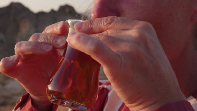 Adult woman tourist enjoying drinking Turkish tea outdoors in mountain valley close-up in travel
