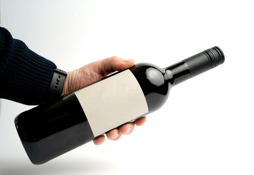 Minimalist wine bottle with blank label held by a hand, showcasing clean packaging and product clarity for branding, tasting concepts, or promotional design presentations.