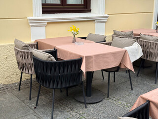Outdoor cafe corner with pastel tablecloths and flowers. Calm elegance, hospitality, and charm of European street dining ambiance.