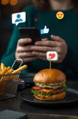 Delicious burger and fries with a mobile user in a cozy dining setting