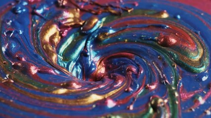Vibrant liquid paint flowing and mixing against a dark background
