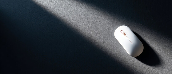 Minimalist white computer mouse casting shadow on textured dark surface with dramatic lighting and diagonal light beam