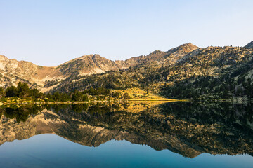 Panoramic view of Lake Aumar at sunrise, reflecting the mountains of the Néouvielle Nature Reserve