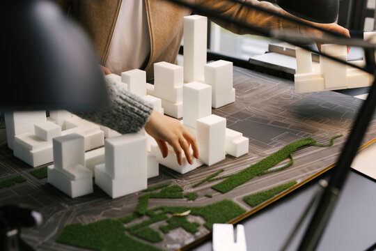 The hands of two architects working with abstract scale models made of styrofoam. 