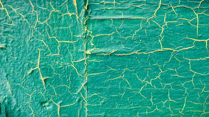 Close-up of vibrant turquoise paint with yellow cracks, creating a distressed abstract texture background
