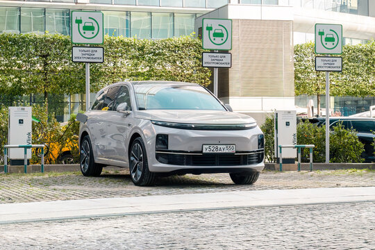 Lixiang Li L6 car parked in an urban lot. Gray hybrid electric SUV parked in city parking with charging station