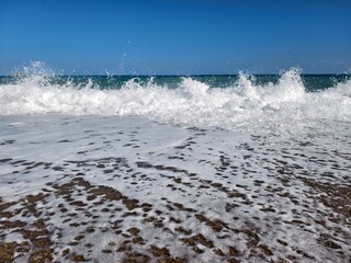 dynamic coastal scene, powerful waves hitting sandy coast, foaming waves crash onto beach shore
