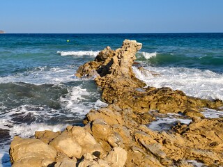 seaside rock formation, rock pier by ocean shore, rocky pier stretches into sea at low tide