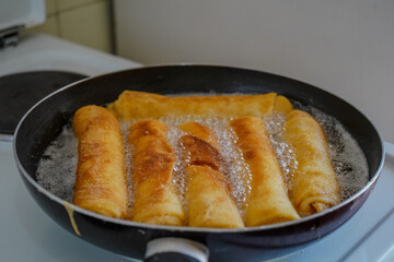 Close-up of piroshki(pirozhki) being fried in a pan filled with hot oil.