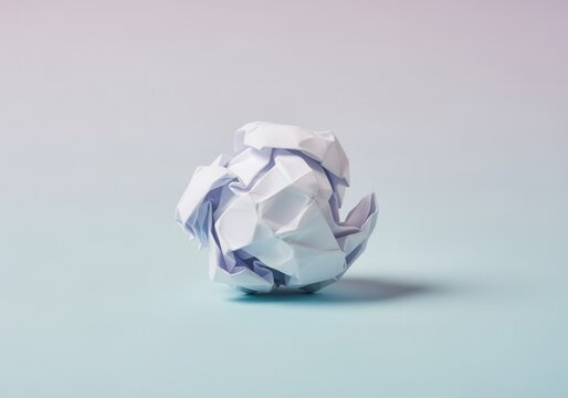 A crumpled ball of white paper on a minimalist background. A concept for mistake, failure, frustration, or a new creative idea. Copy space for text