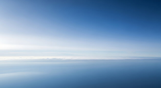 Aerial view of a vast blue ocean and sky with thin white clouds image