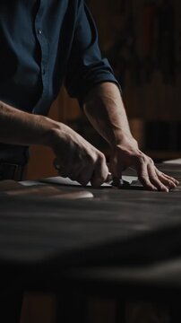 Garment production process. Unrecognizable male tailor passing around patterns on leather piece, preparing blanks