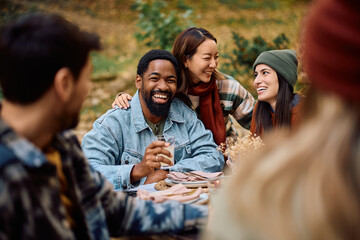 Happy black man enjoying in gathering with friends on patio in autumn.