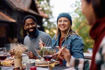 Happy woman gathering with her friends at picnic table on patio in autumn.