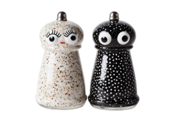 A quirky pair of ceramic salt and pepper shakers: speckled white with eyelashes, and black with white dots and wide eyes. background removed