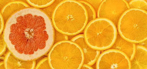 a lot of bright orange circles of oranges, with one large circle of grapefruit with deep pink flesh in the left part of the composition