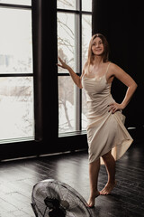 Fototapeta premium Happy young woman in yellow satin dress dancing barefoot