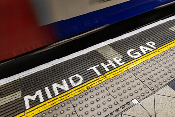 Mind the Gap - Achtung Spalt - Warnhinweis mit vorbeifahrendem Zug in London