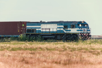 Freight train transporting cargo containers through rural landscape