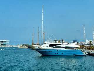 Fototapeta premium Luxury yachts docked at a marina on a sunny day near the coastline with clear blue skies and calm waters