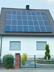 Solar panels capture sunlight on a suburban home roof during a cloudy afternoon in a peaceful neighborhood