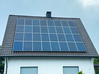 Fototapeta premium Innovative solar panels harnessing renewable energy on a suburban house roof in bright daylight