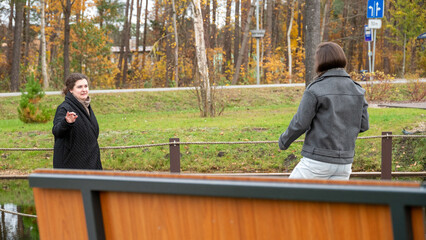 Friends Enjoying a Conversation by the Pond in a Quiet Park During Autumn Afternoons