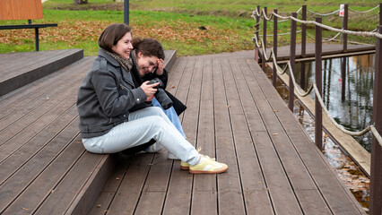 Friends Enjoying Photography by the Lakeside in Autumn While Sitting on Wooden Steps