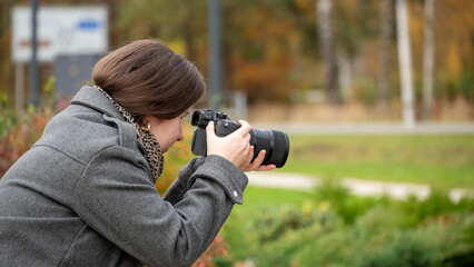 Woman Using a Camera to Capture Nature in a Park During Autumn With Colorful Leaves