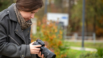 Woman Takes Careful Aim With Camera in a Park During Autumn Foliage