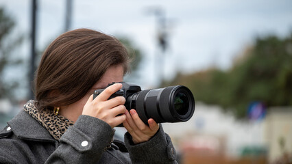 Young Woman Capturing Moments With a Camera During an Outdoor Event on a Cloudy Day