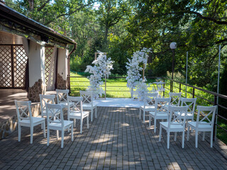 Wedding arch with white chairs and flowers in the park.
