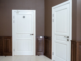 Interior of a hotel room with two white doors and a wooden door