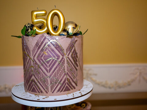 Birthday cake with number 50 in pink and gold colors on the table