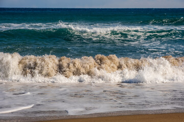 Sea wave breaks on sandy beach with clouds sky on Mediterranean coast of Mersin province, Atakent