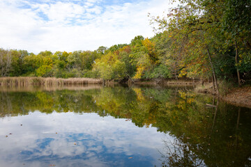 Reflections of the cloudy October sky and bright fall colors perfectly mirror on a quiet Waukesha County pond.