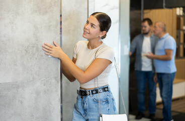 Girl looking to buy floor ceramic tiles in materials section of hardware store