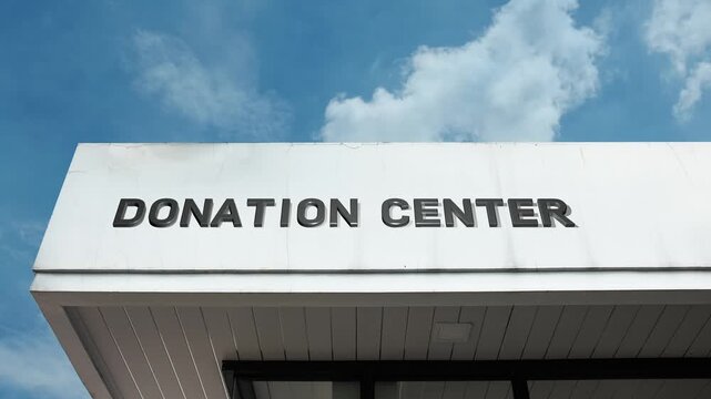Donation center word sign displayed on building facade under clear blue sky, showcasing a charitable facility dedicated to receiving and distributing donations for community support.