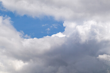 Cloud texture. Hole in thick white clouds with blue sky shining through. Cloudy sky background