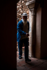 Elderly man walking through an ancient doorway in a historic building, with the stone steps visible in the background