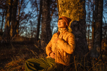 Person meditating in forest at golden hour
