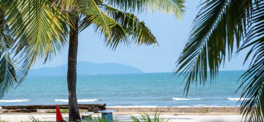 Tropical beach view framed by palm trees under clear blue sky